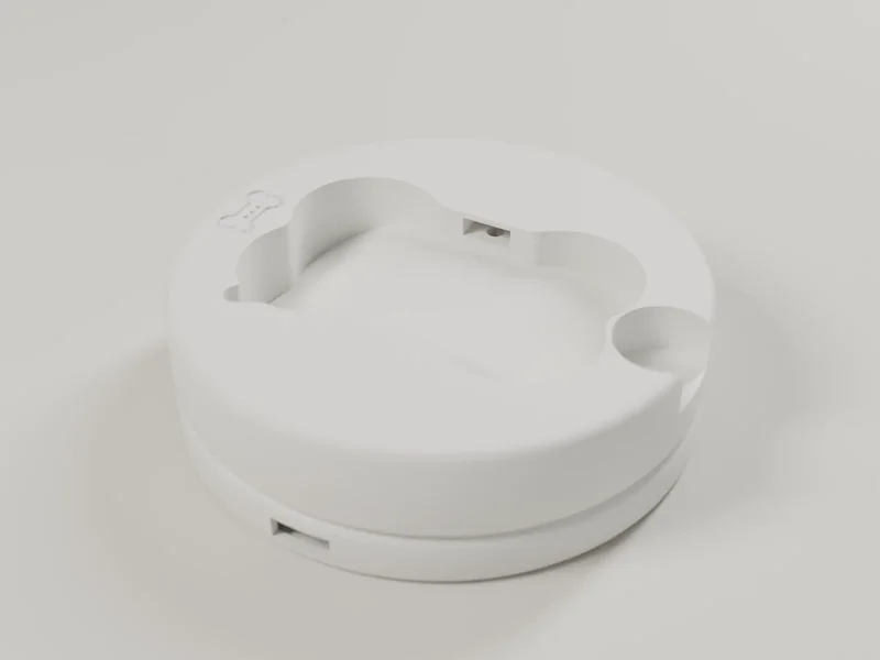 Render of an empty white Lite base from above: a bone-shaped pocket with the charging contacts at its edge.